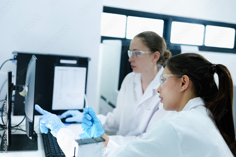 Obraz premium Team of female scientists analyzing digital pathology slides on computer. Caucasian and Asian researchers reviewing histology data for medical diagnosis in modern lab.