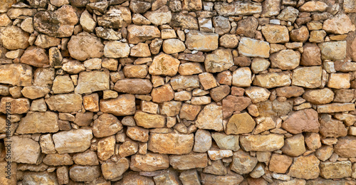 Old rustic dry stone wall background with natural warm earth tones
