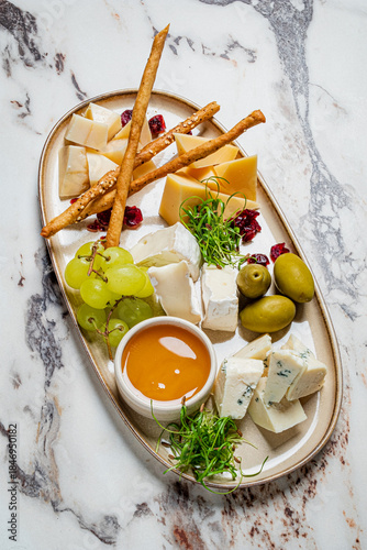 A beautiful cheese platter features assorted cheeses, grapes, olives, and honey for sharing
