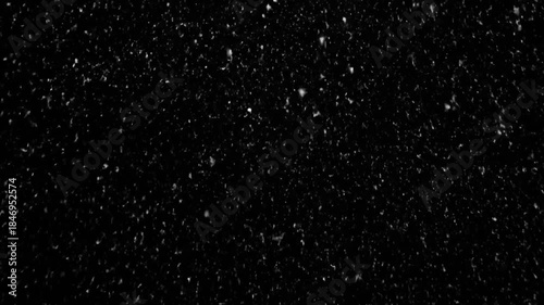 Heavy snowfall continues falling against a dark background in this continuous video clip