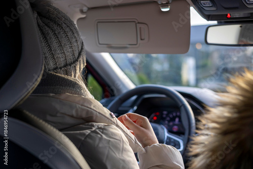 Young girl drives a car on the road in the afternoon sun.