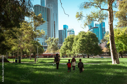 A family joyfully walking in a lush park with a vibrant city skyline backdrop