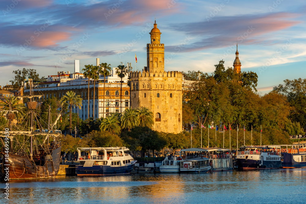 Fototapeta premium Tower of Gold (Torre del Oro) on Guadalquivir river embankment at sunset, Seville, Spain