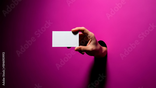 Hand holding blank business card mockup through magenta background