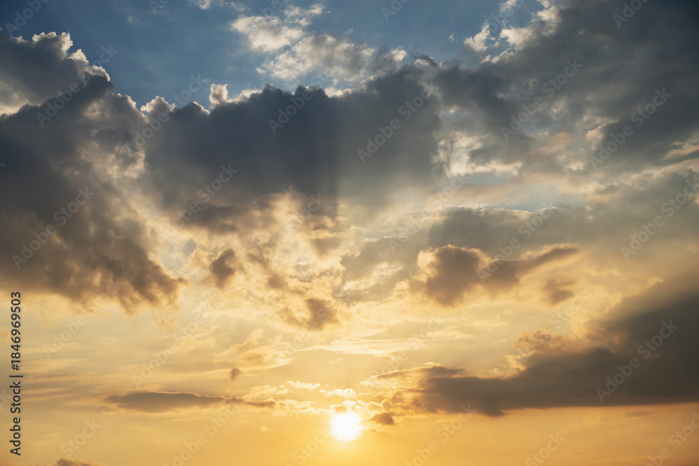 Fototapeta premium Dramatic sky with clouds and golden sunlight at sunset. Natural background showing peaceful evening atmosphere, hope and inspiration. Ideal for nature, weather and spirituality.