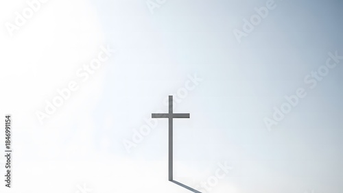 A solitary cross stands against a bright sky, casting a long shadow on a clear day