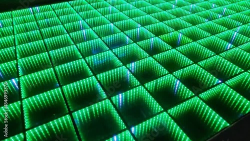 A shimmering multicolored interactive LED dance floor where each square panel glows and flickers brightly.