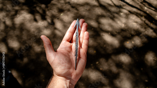 A hand holding a unique arrowhead