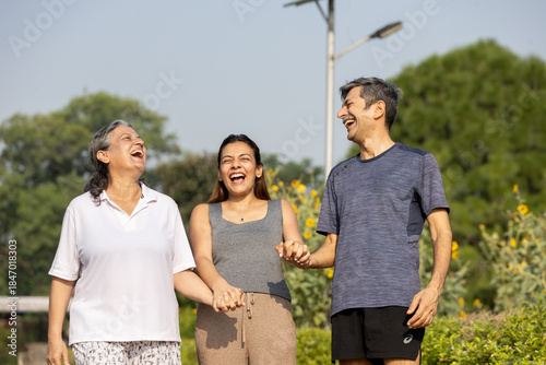 Smiling Indian multi-generation family enjoying a morning walk in a green park.