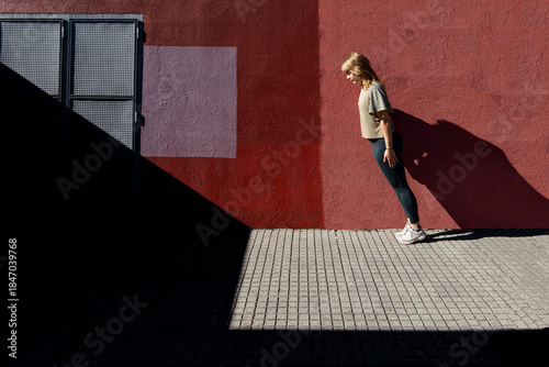 Autumn body pose against urban wall in sunlight
