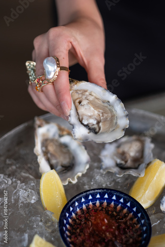 Hand with elegant rings holding fresh oyster