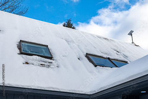 Tableau sur toile Snow-covered roof with skylight windows on modern house exterior in winter