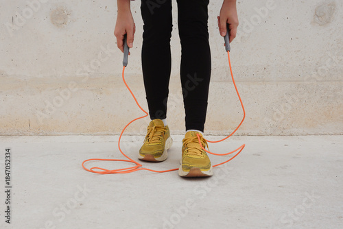 Outdoor jump rope workout with concrete floor and wall, hands holding skipping rope, simple daily fitness activity, self-improvement routine, active lifestyle, consistency, and healthy habits.