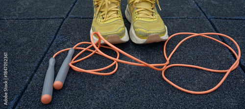 Jump rope and sneakers on dark sports floor, simple daily fitness routine, workout preparation, active lifestyle, consistency, self-improvement, and healthy habits.