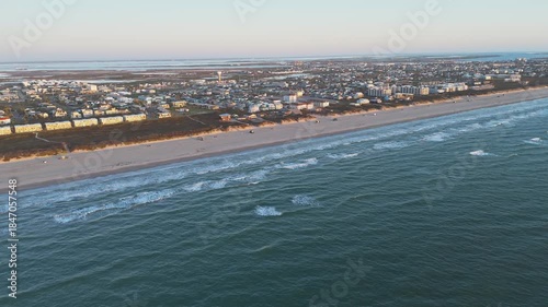 Aerial view of the Port Aransas Beach Park, with the beach and the waves under a sunny sky, people gather for enjoyment and leisure.