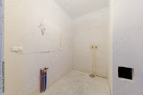 Unfinished bathroom interior with exposed pipes and wires