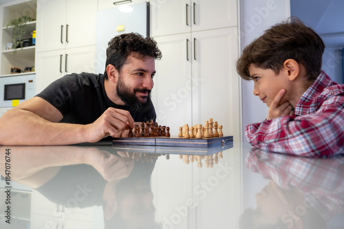 father and son playing chess at home