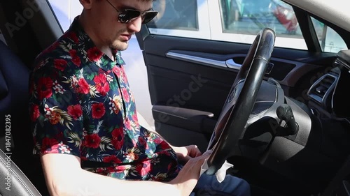 A man wipes the steering wheel of a car with a napkin at a car wash.