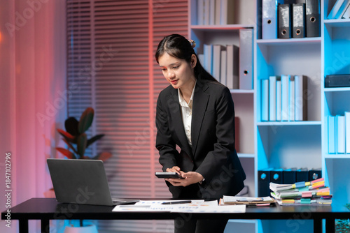 Fotografi Professional at Work: A poised individual, dressed in business attire, stands attentively in a modern office space, engrossed in their work