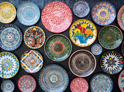 Lots of decorative color ceramic plates with traditional Uzbek ornaments hanging on wall . Not ai