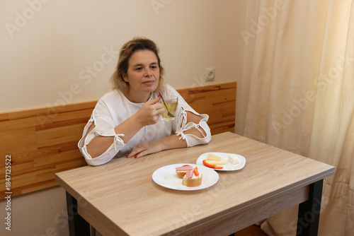 Woman drinking tea and eating sandwiches while sitting at the table