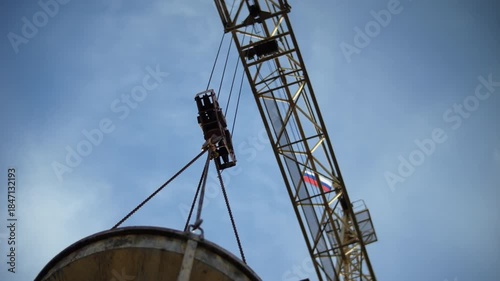 Tower crane lifting concrete bucket at construction site