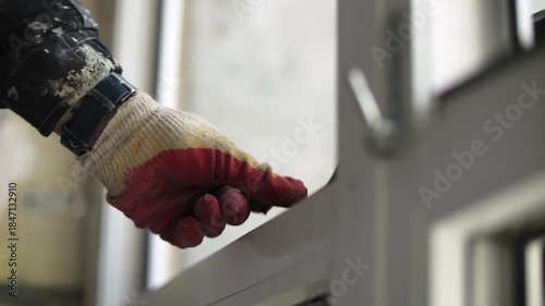 Worker adjusting plastic window frame installation