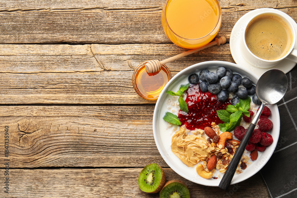 Naklejka premium Healthy breakfast. Oatmeal with nuts, berries, yoghurt, coffee and orange juice on wooden table, flat lay. Space for text