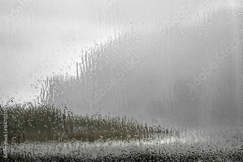 Blick durch eine regennasse Fensterscheibe – Starkregen prasselt gegen das Glas