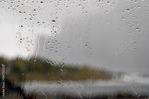 Blick durch eine regennasse Fensterscheibe – Regenwasser läuft am Glas herunter