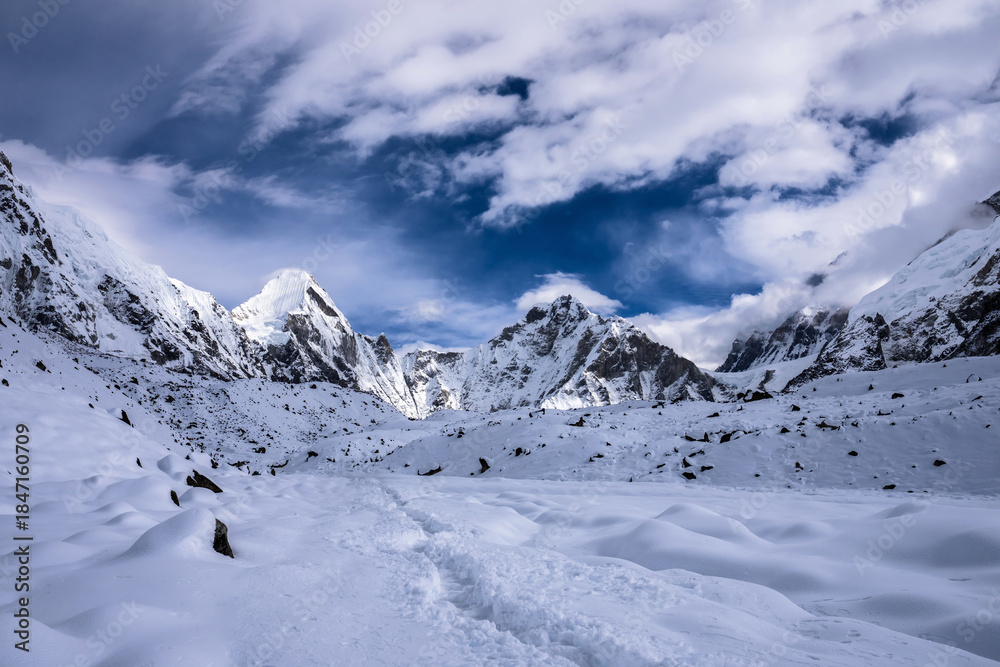 Fototapeta premium Trekking route to Lobuche after snowfall. Lingtren and Khumbutse peaks behind snowy valley. Everest base camp trekking, Nepal.