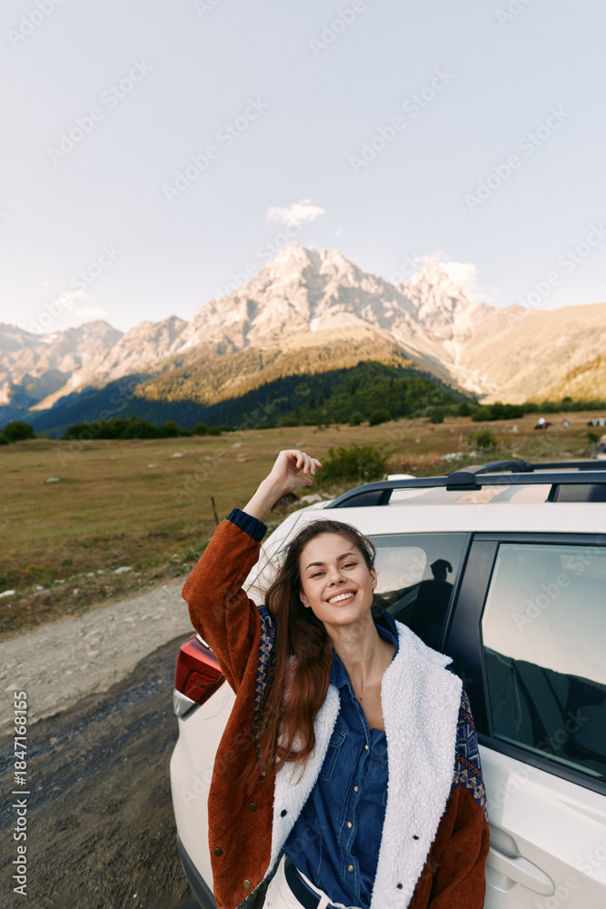 Naklejka premium Woman leans from car with a bright smile beside a mountain road during travel, enjoying the landscape and nature. Casual jacket, relaxed portrait capturing outdoor journey and scenic freedom.