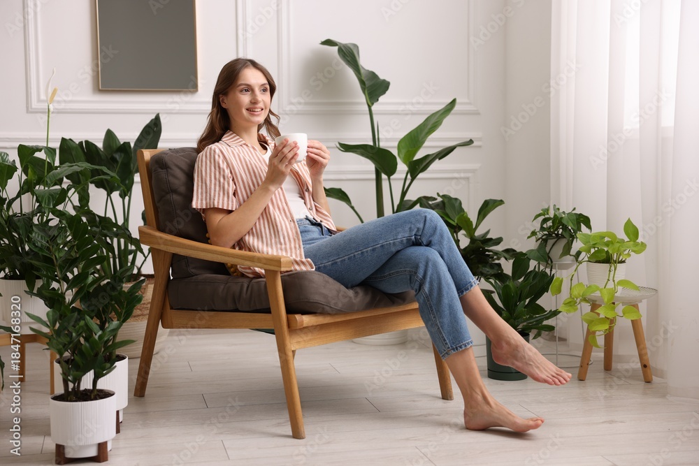 Fototapeta premium Woman with cup of aromatic coffee in armchair at home