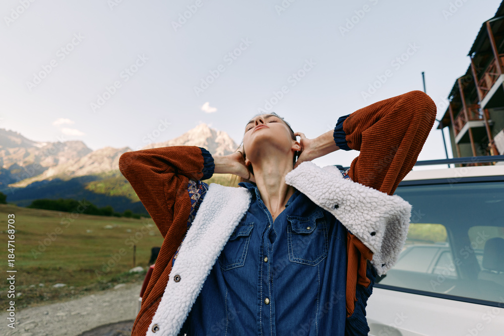 Fototapeta premium Woman jacket outdoors by car on road with mountain scenery, enjoying travel and relaxation, a scenic trip moment of freedom and adventure in nature landscape during holiday journey.