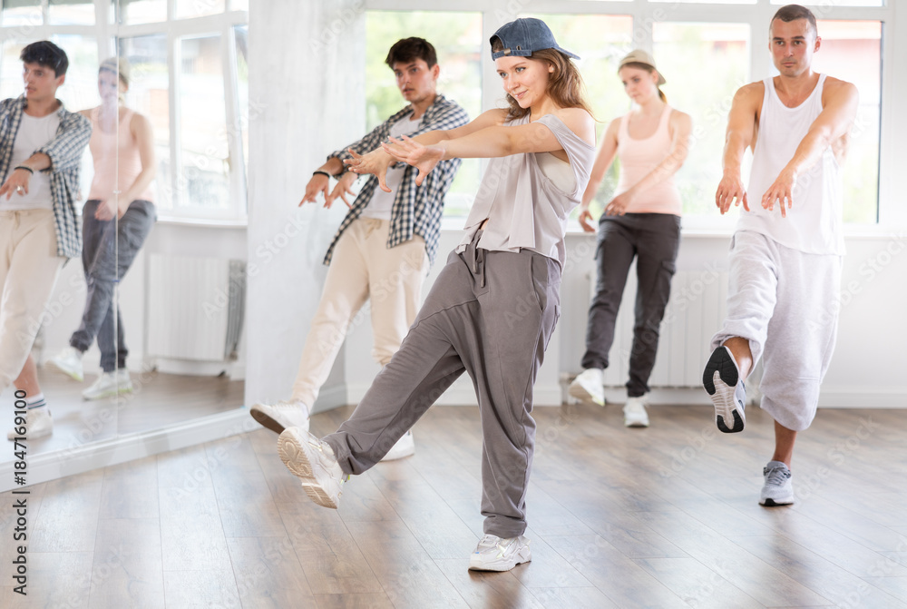 Fototapeta premium Active young girl practicing kicking move of hip-hop in training hall during dancing classes