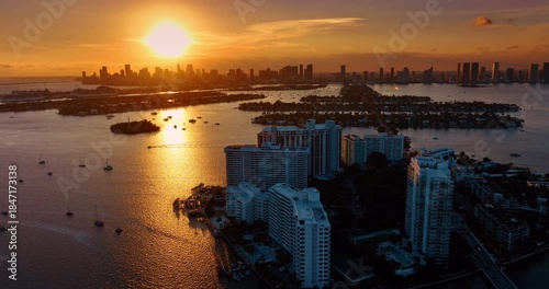 Boats and yachts on the waterscape of Biscayne Bay dazzled by setting sun. Drone footage over the islands of Brickell Key, Miami, USA.