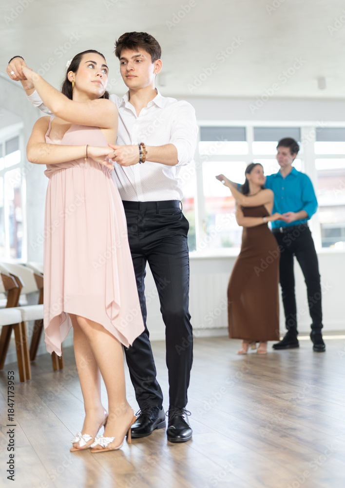 Naklejka premium Couple of young guy and young woman dancing waltz in studio