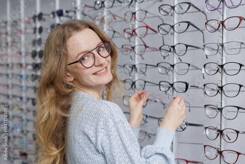 Φωτογραφία Smiling woman selecting eyeglass frames in optical store eyewear shopping and vi