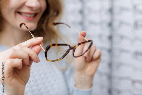 Obraz na płótnie Close up woman holding tortoiseshell eyeglass frame in optical store choosing ey