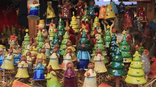 Ceramic Christmas ornaments displayed at a European holiday market, glowing in warm winter lights and creating a cozy festive atmosphere.