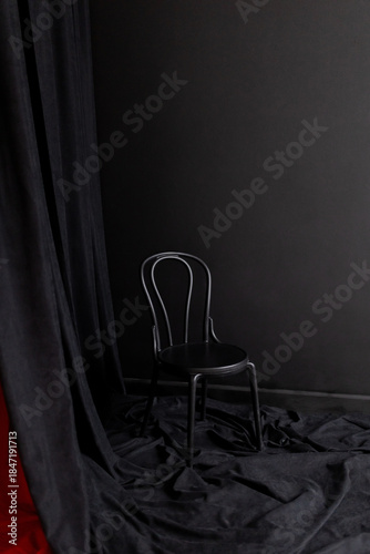 Black bentwood chair on dark fabric backdrop