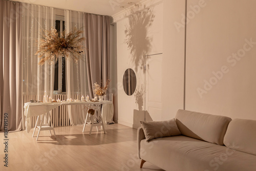 Elegant beige interior with a minimalist sofa, pampas grass decor, and a beautifully set table under warm light