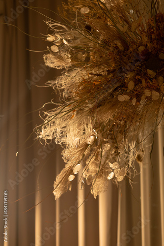 Close-up of a decorative dried flower arrangement in warm lighting against soft curtains