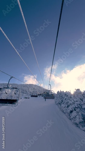 Ski chairlift at Killington Mountain, Vermont. Riding a lift in winter while snow skiing and snowboarding with white snowy trees and mountains. Vertical 4K video.