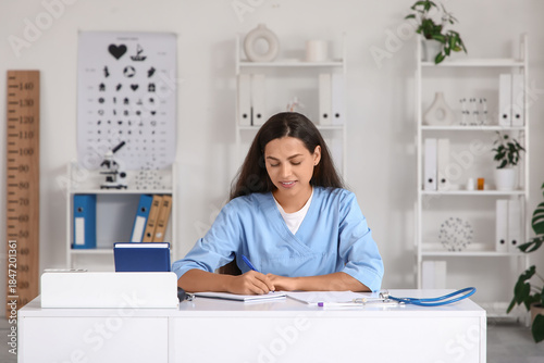 Young female doctor writing...