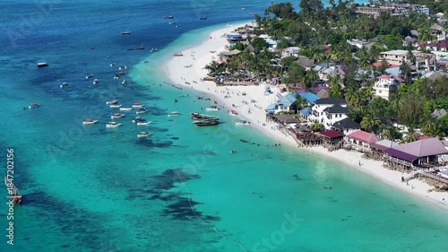 4k aerial video footage of Nungwi Beach -  popular tourist destination- with people on the white sand beach and in the turquoise water, located in Nungwi village in most northern part of Zanzibar
