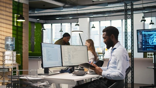 Foto Admin in tech startup office using PC, compiling software patches to fix bugs, troubleshooting backend operations