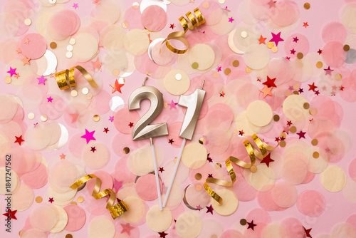 Golden wax candles in the shape of the number 21 on pink confetti background. Twenty one birthday concept. Selective focus