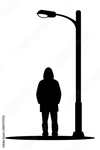 Silhouette of person standing under a tall street lamp post at night outdoors