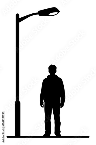 Silhouette of a person standing beneath a tall street light in darkness